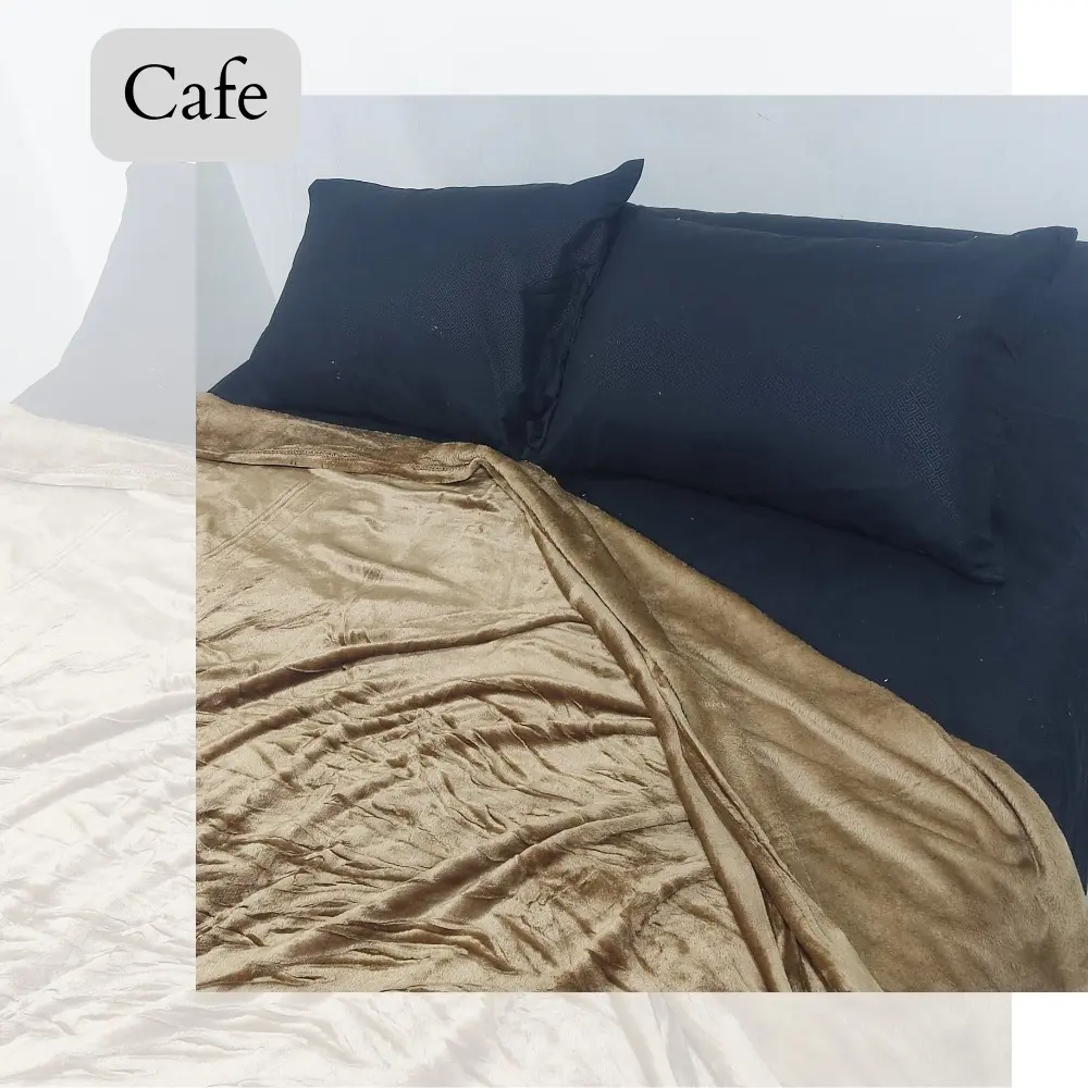 Cobija piel de durazno color café, textura suave, sobre cama con almohadas negras.