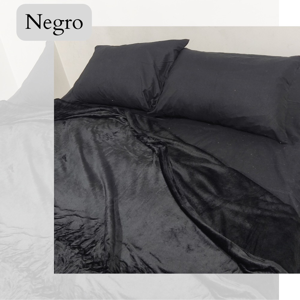 Cobija piel de durazno negra, tamaño 1.40, textura suave y mullida, con dos almohadas negras encima.