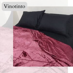 Cobija piel de durazno vino c/ 2 almohadas negras con relieve en cama.
