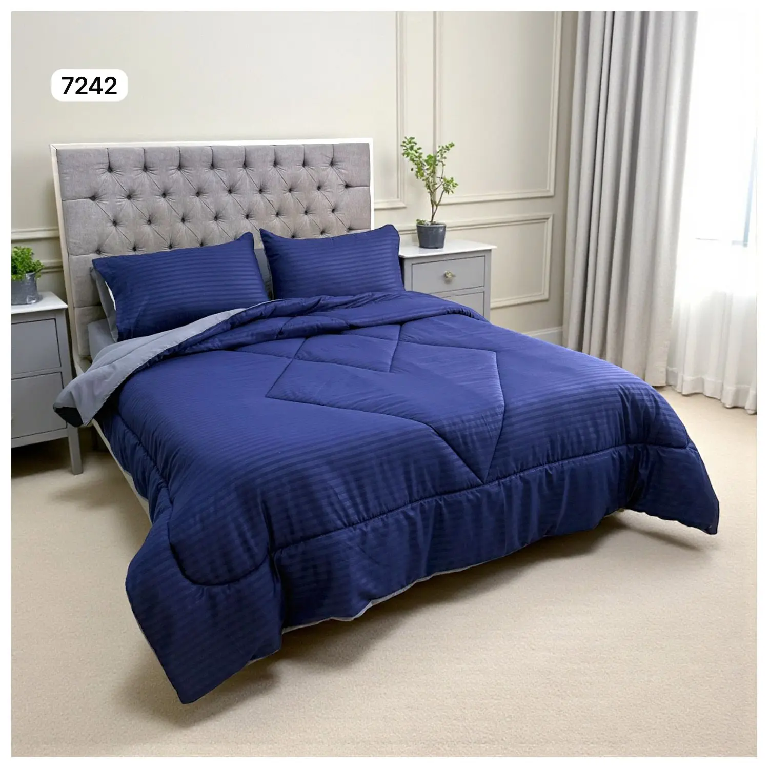 Edredón doble faz azul marino con rayas verticales y diseño acolchado, sobre cama doble con almohadas a juego.