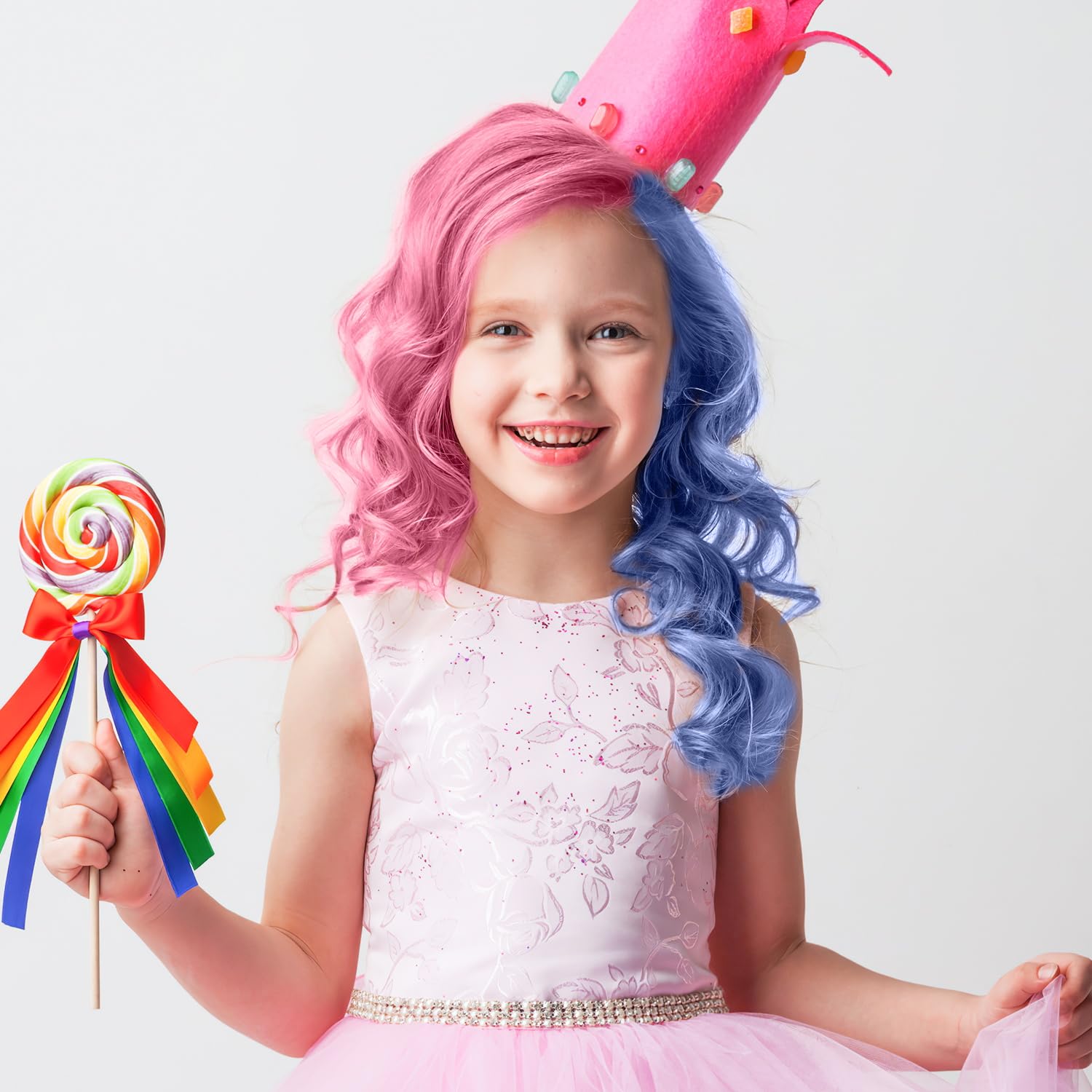 Niña con cabello rosa y azul, corona rosa y vestido, sostiene paleta de colores arcoíris.