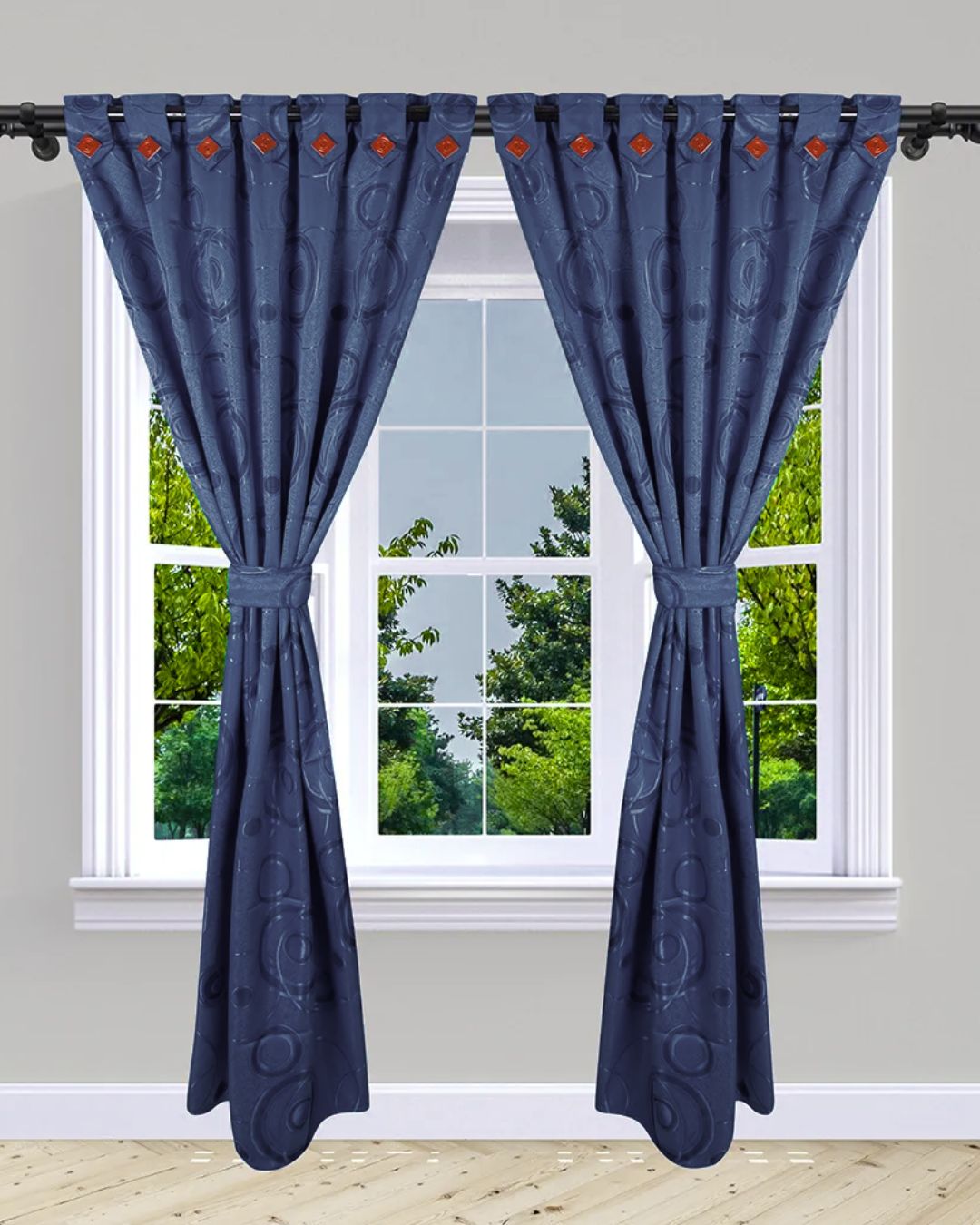 Cortinas Jacquard azul marino con patrón circular y ojales naranjas, decoran una ventana con vista a árboles.