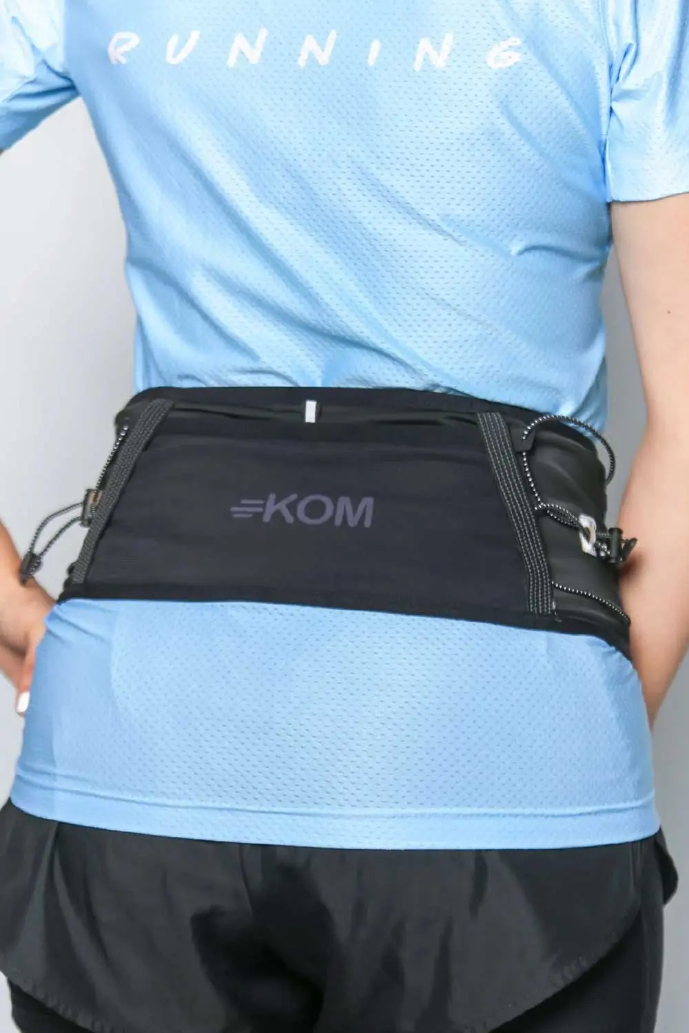 Riñonera deportiva negra para correr con logo KOM, ajuste en cintura, ideal para deportistas.