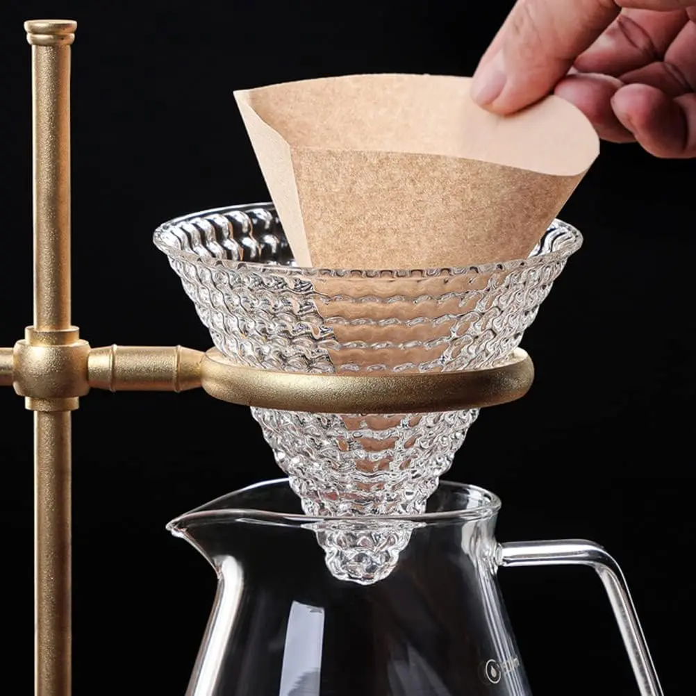 Filtro de café V60 #2 en papel marrón, para cafetera de goteo, con soporte dorado y jarra de vidrio.