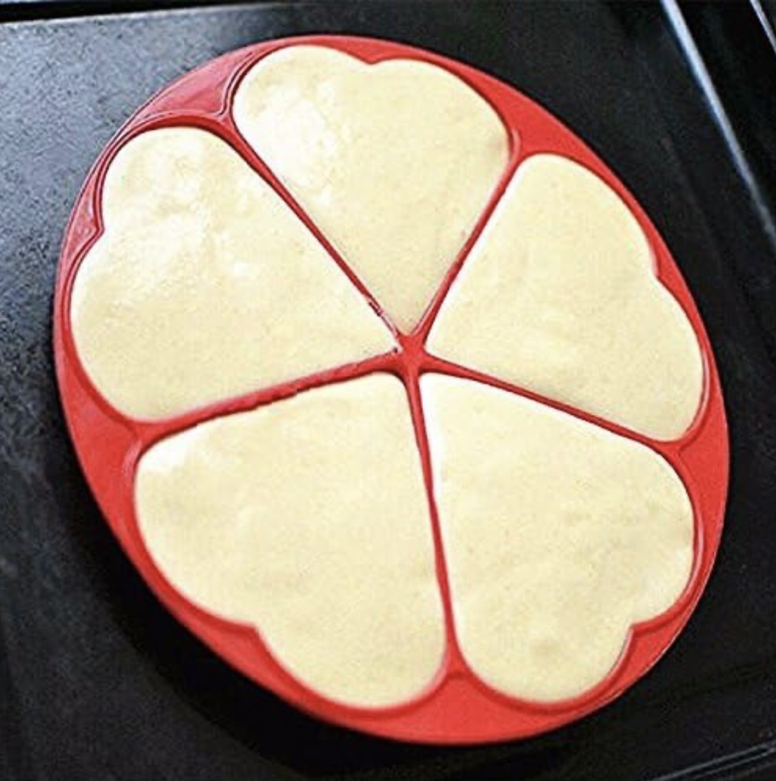 Molde de silicona rojo con 5 cavidades en forma de corazón, listo para preparar waffles.