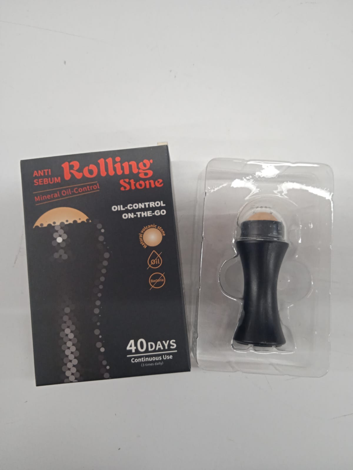 Roll-on quita grasa portátil negro con piedra volcánica, ideal para control de brillo facial.