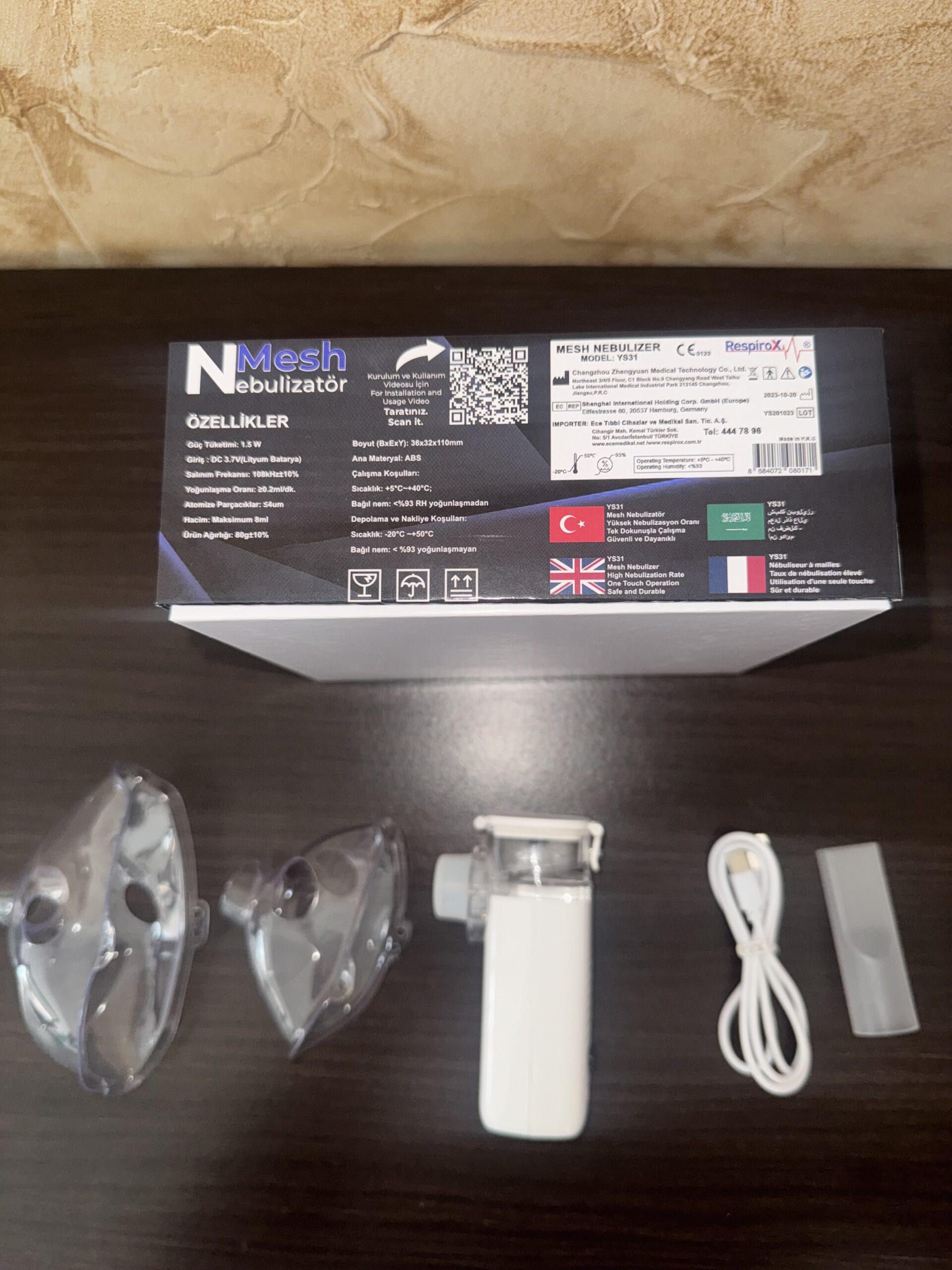 Nebulizador ultrasónico portátil blanco y transparente, incluye mascarillas, cable USB y estuche.