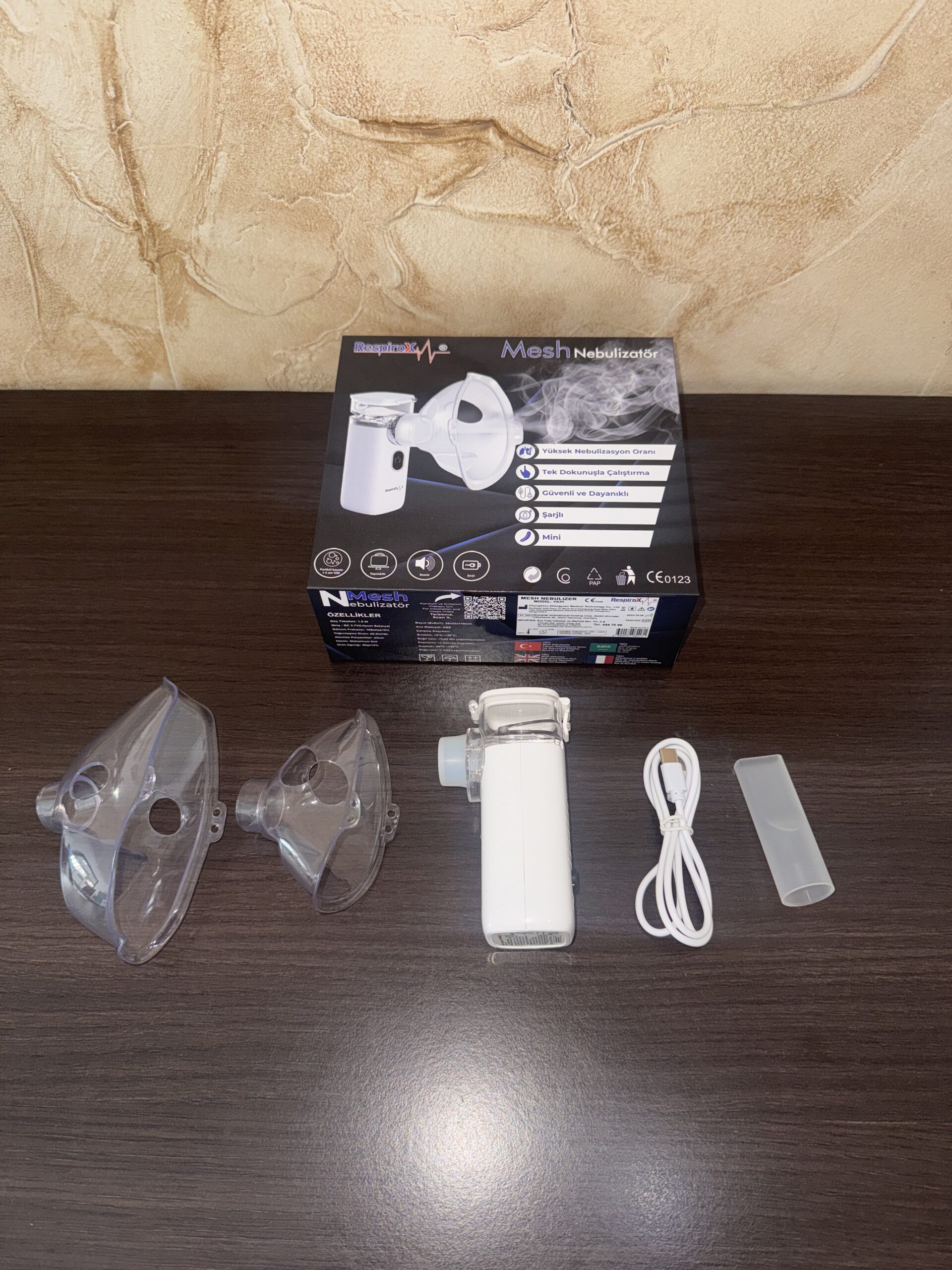 Nebulizador ultrasónico portátil blanco con mascarillas transparentes, cable USB y estuche.