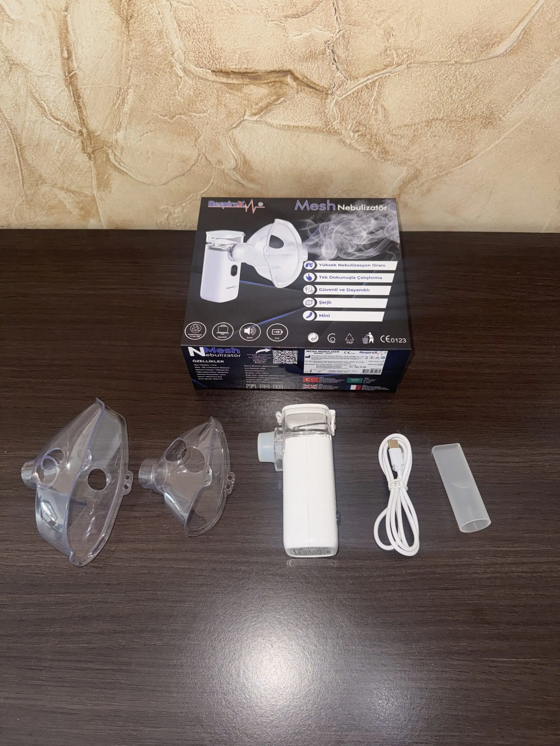 Nebulizador ultrasónico portátil blanco con mascarillas transparentes, cable USB y estuche.