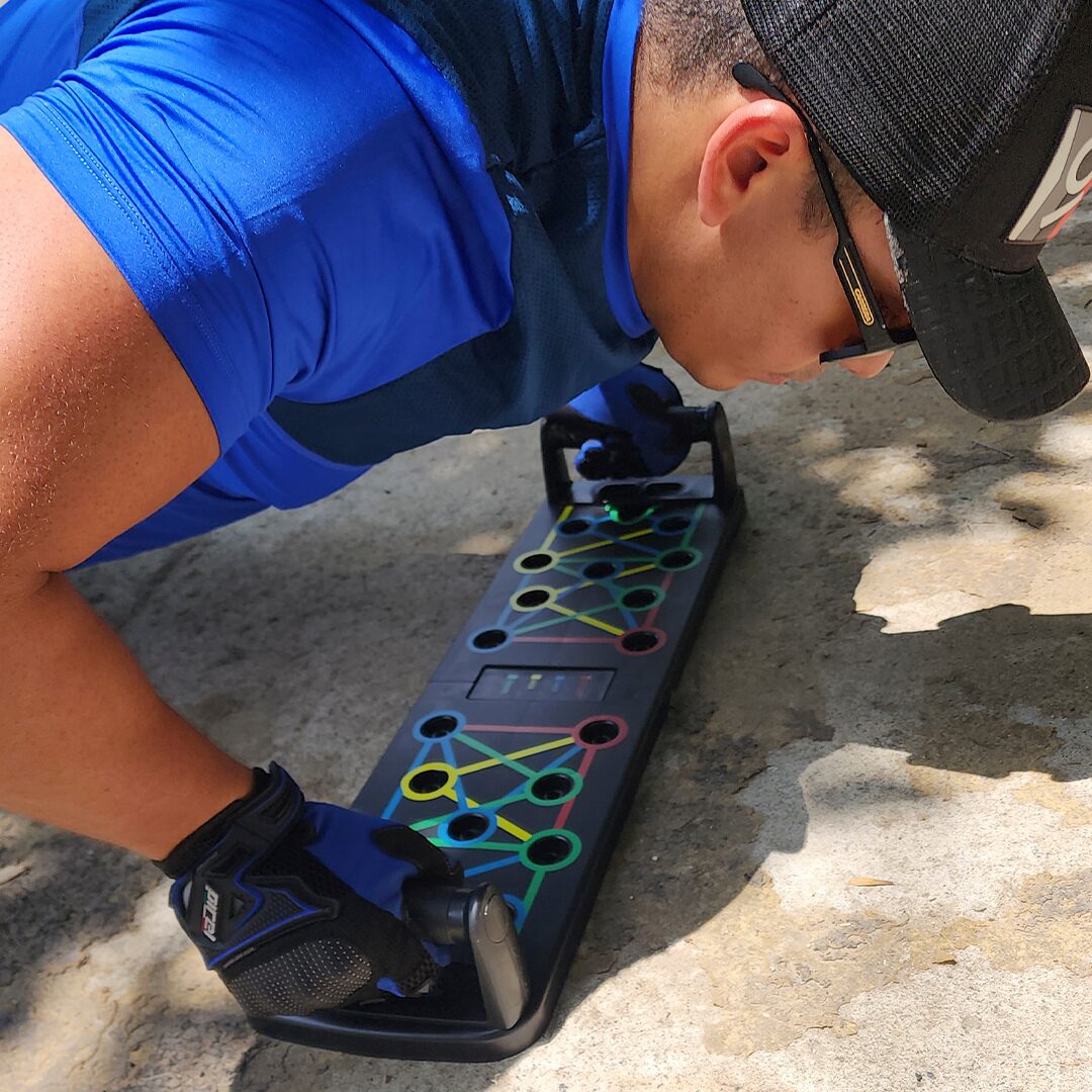 Hombre entrenando tren superior con tabla push up plegable multifuncional en exterior.