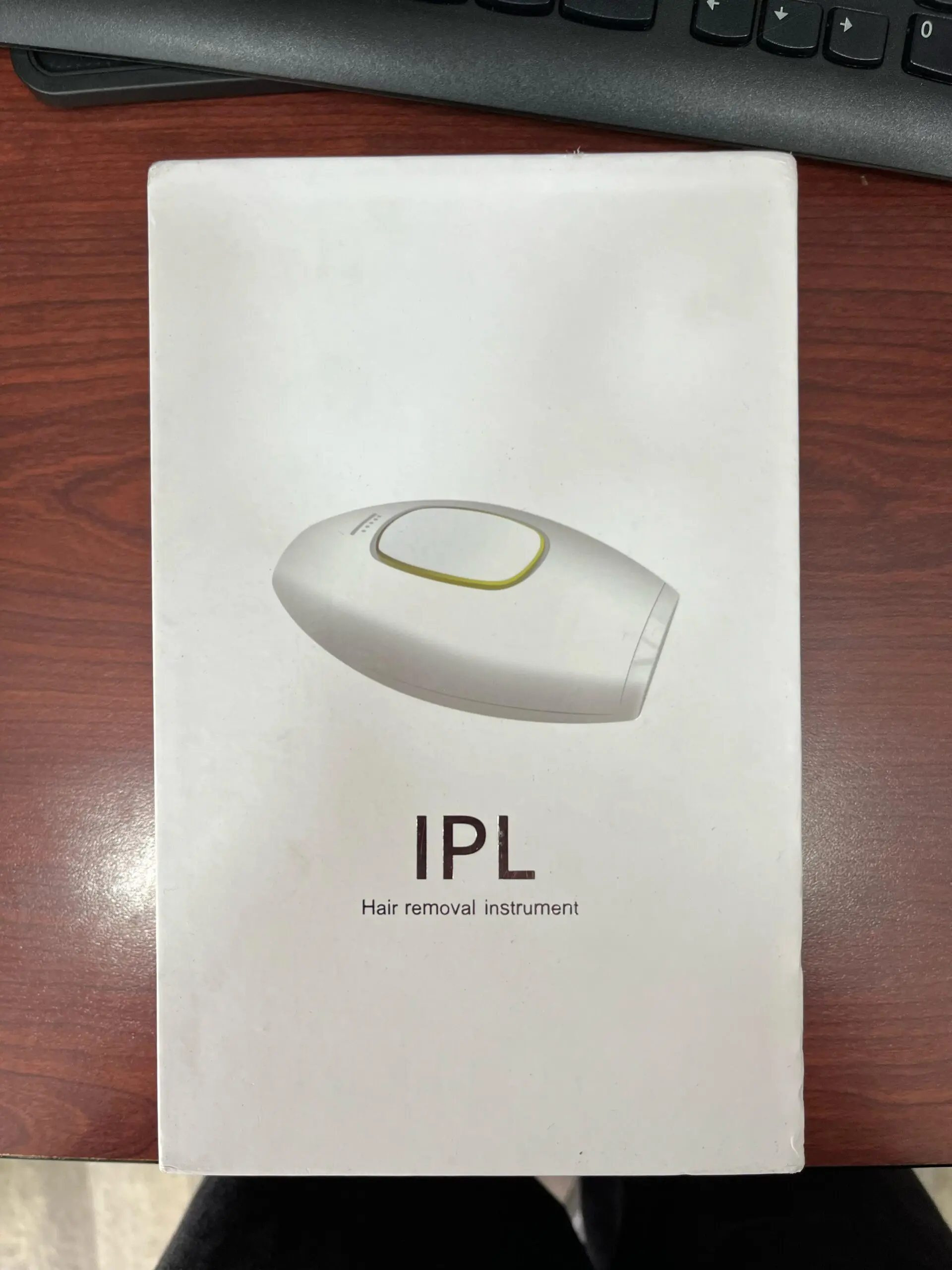 Depiladora láser IPL blanca para cuerpo y rostro, con ventana de tratamiento amarilla y texto "IPL Hair removal instrument".