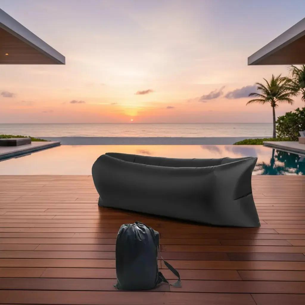 Sofá inflable portátil negro de nylon ripstop, ideal para exteriores, junto a piscina al atardecer.