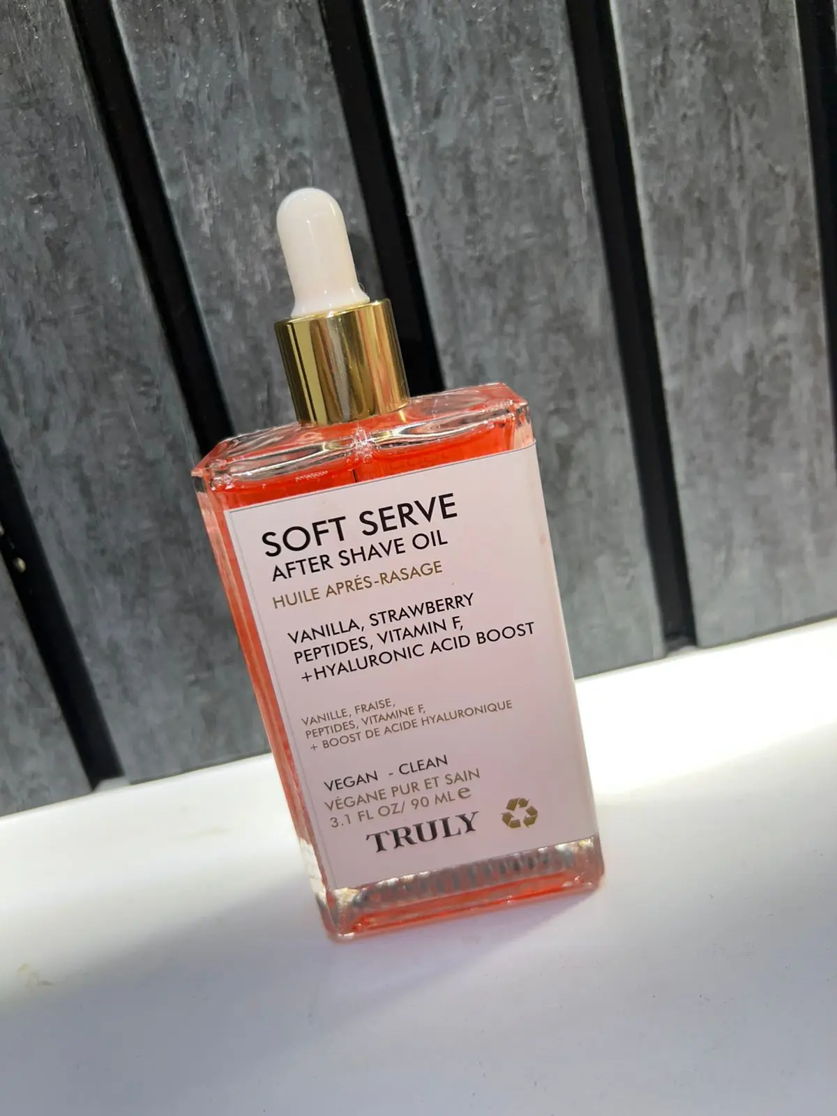 Aceite para después del afeitado Soft Serve de Truly, 90 ml, con extractos de vainilla y fresa, en envase de vidrio con gotero dorado.