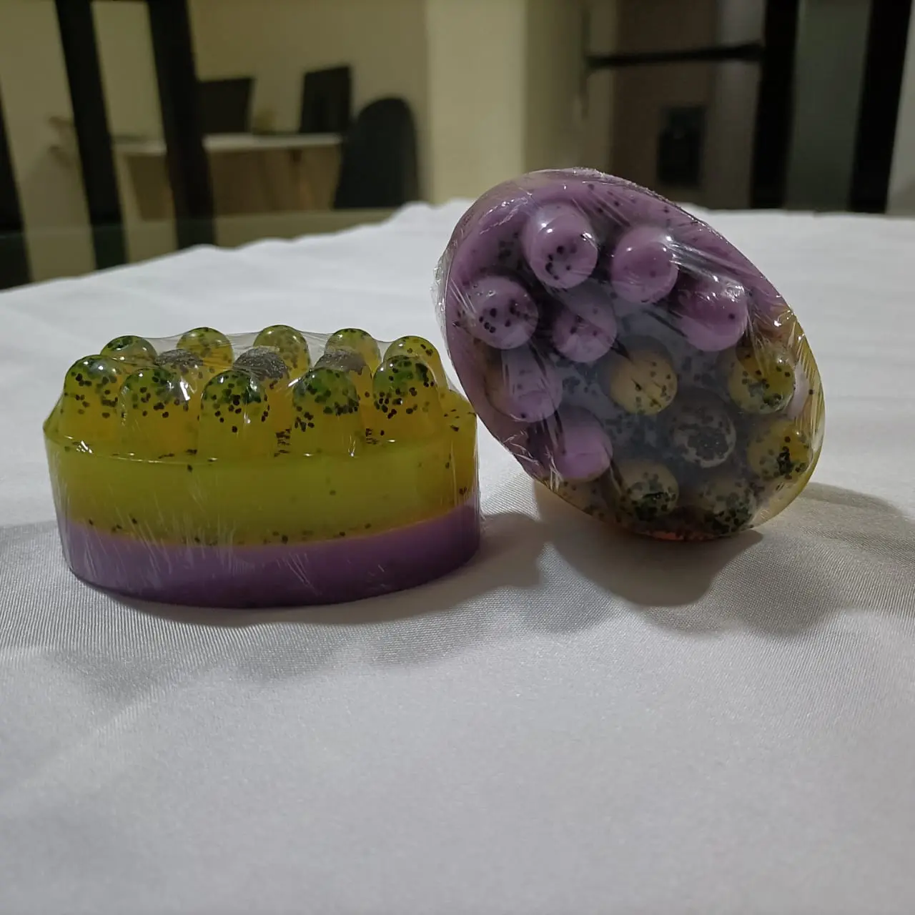 Jabones masajeadores de amapola/maracuyá, uno redondo amarillo y morado, otro ovalado morado y amarillo, con semillas, 125Gm