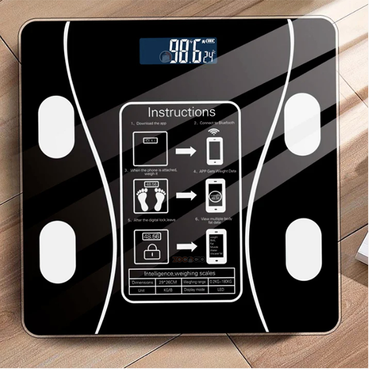 Pesa digital de baño negra con pantalla LED mostrando 98.6 y 24°C, instrucciones de uso y tabla de especificaciones.