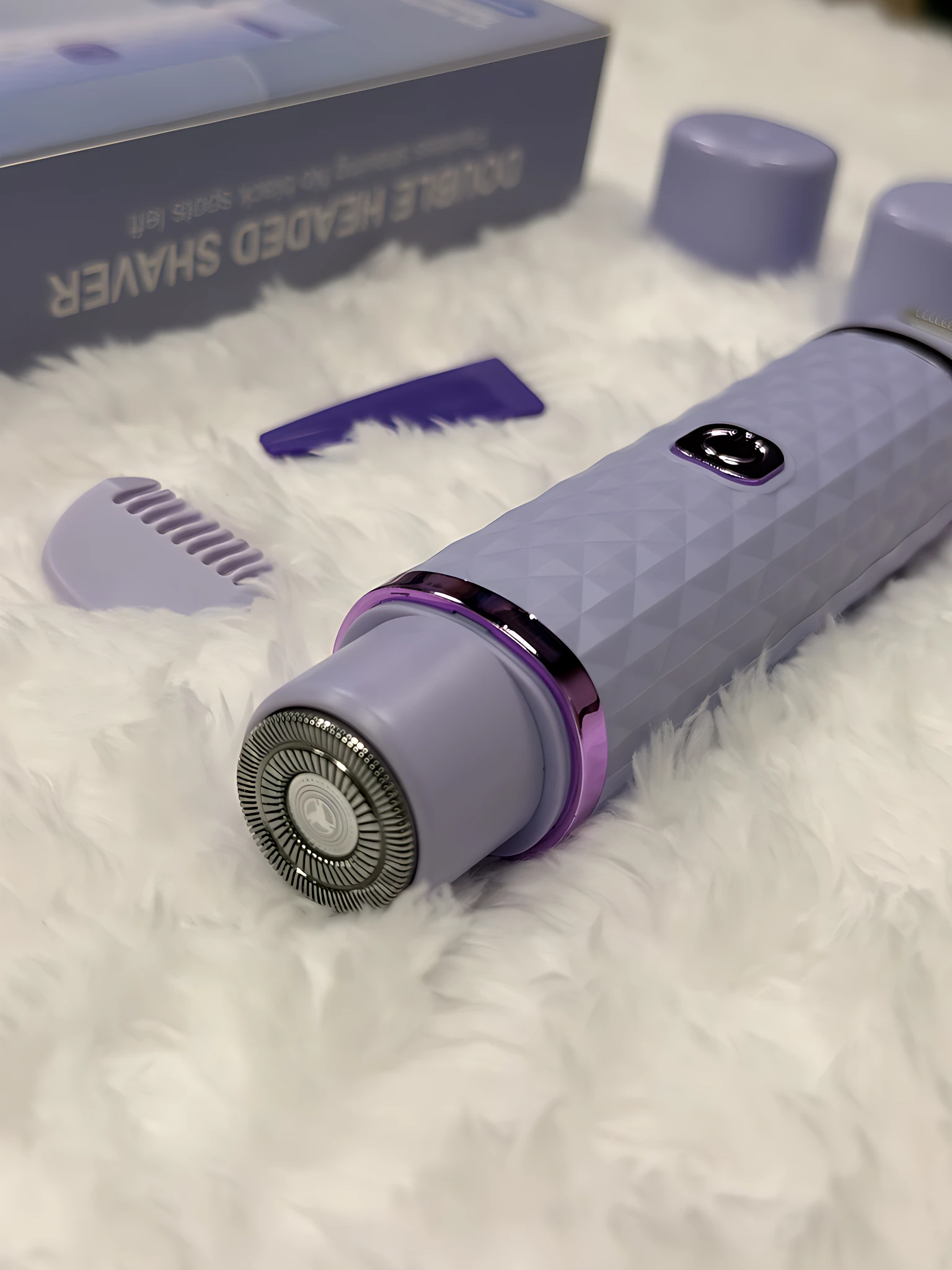 Afeitadora depiladora facial y corporal 2 en 1, color lavanda, con cabezal de corte y accesorios, sobre fondo blanco peludo.