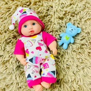 Muñeco bebé con pijama de helados y gorro, junto a un osito de plástico azul.
