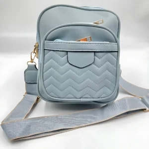 Bolso manos libres azul pastel acolchado con dos compartimentos y correa ajustable.