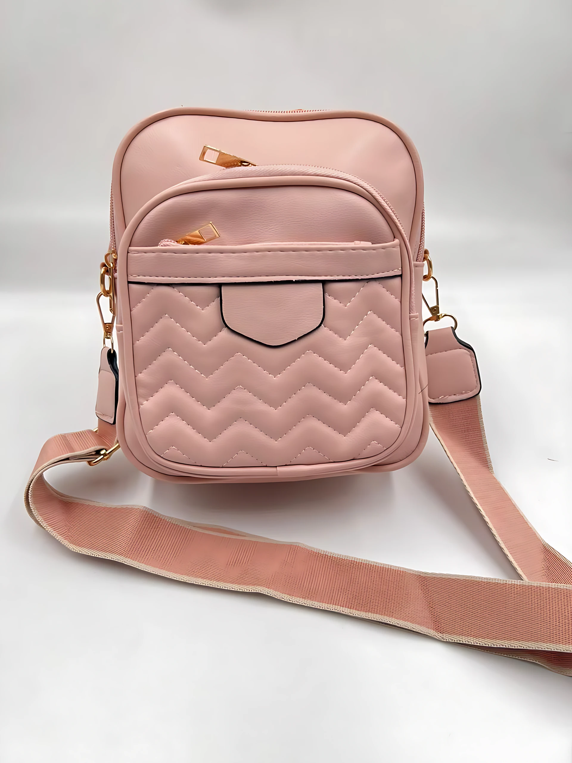 Bolso manos libres mujer rosa palo, acolchado en zig-zag, dos compartimentos y correa ajustable.