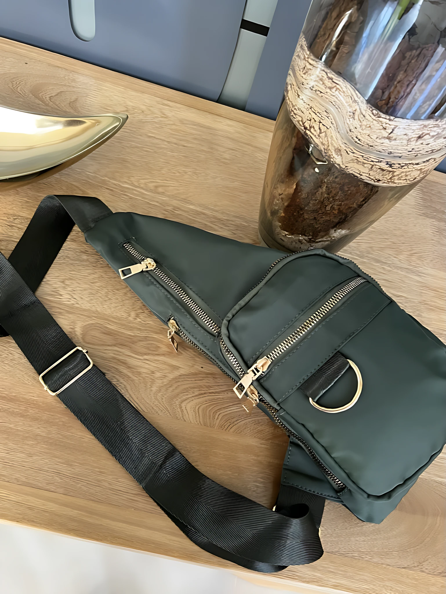 Bolso bandolera impermeable Spice verde oscuro con correa negra ajustable y detalles dorados, ideal para llevar esenciales.