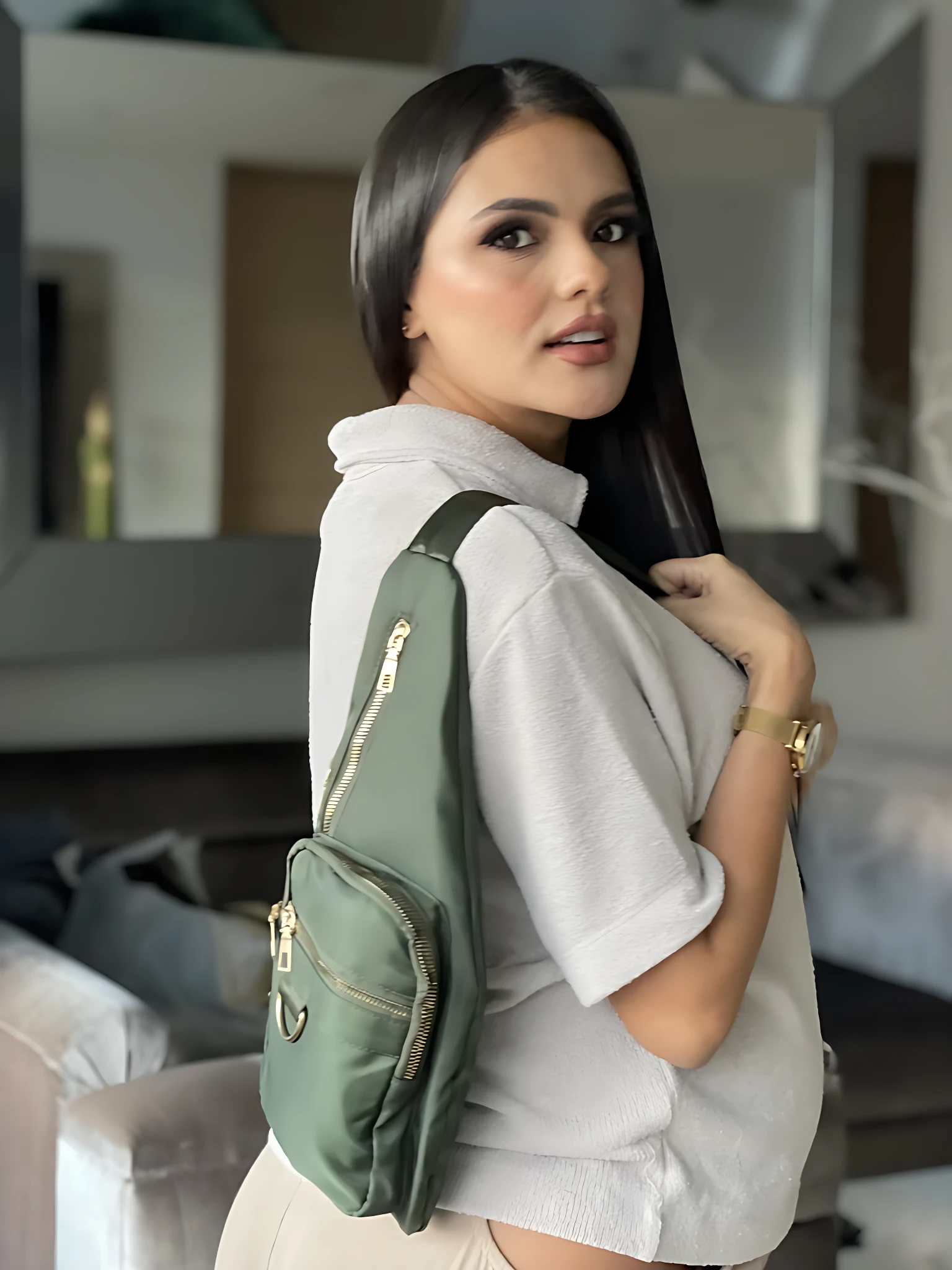 Mujer con bolso bandolera Spice verde, impermeable, diseño moderno con cremalleras doradas.