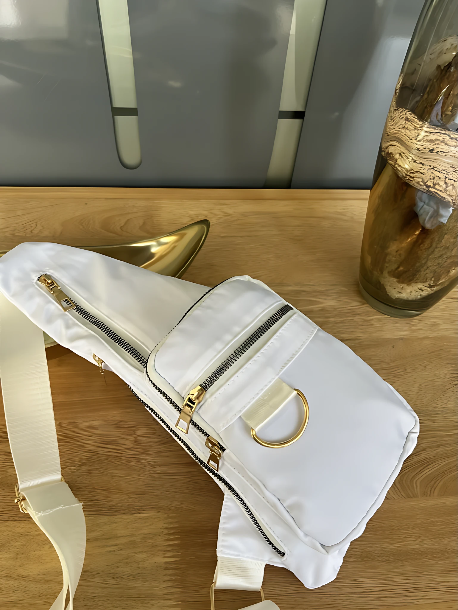 Bolso bandolera blanco impermeable con cremalleras doradas y asa ajustable, perfecto para uso diario.