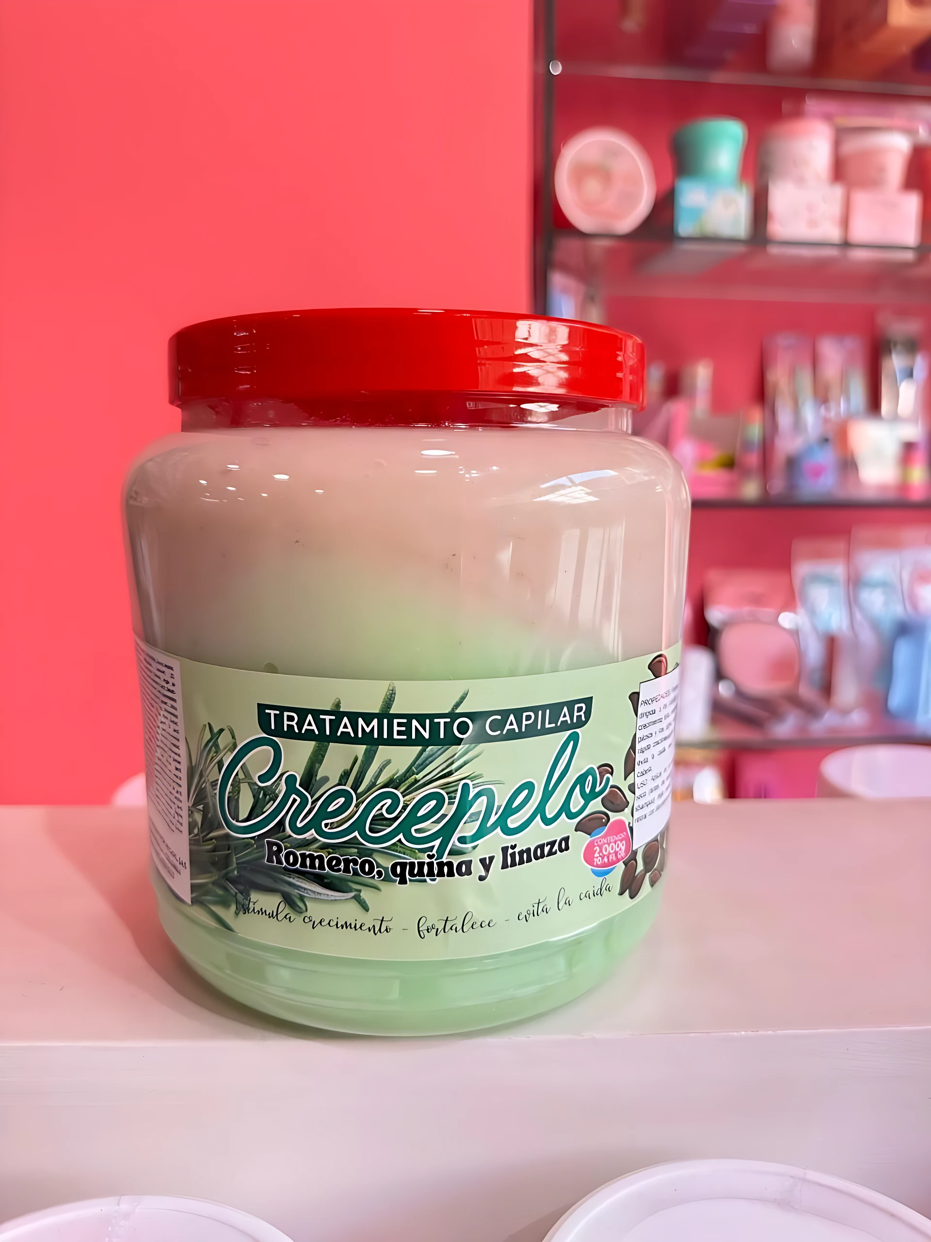 Crecepelo tratamiento capilar en tarro grande con tapa roja, crema verde claro y etiqueta con romero, quinua y linaza.