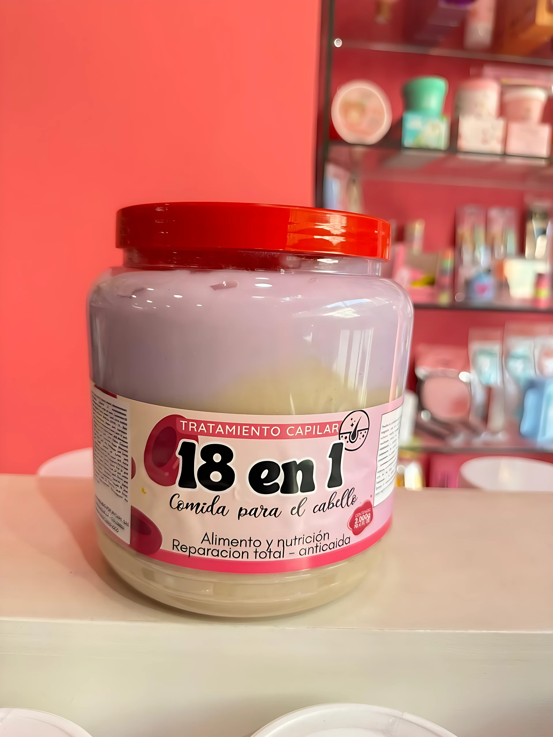 Tarro grande de tratamiento capilar "18 en 1" de 2000g, color lila y crema, con tapa roja.