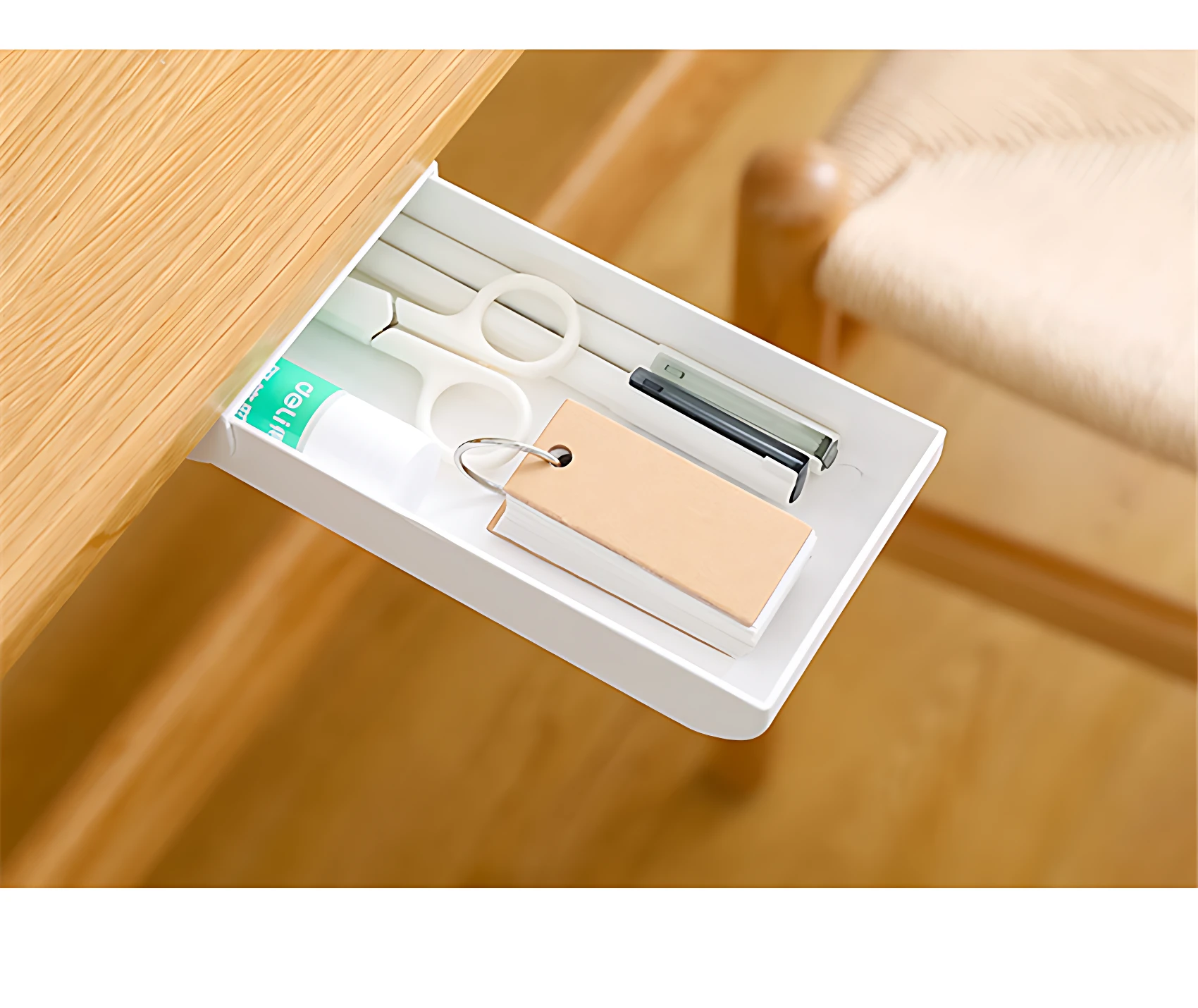 Cajón blanco adhesivo compacto para escritorio con tijeras, bolígrafo y mini libreta sobre superficie de madera.