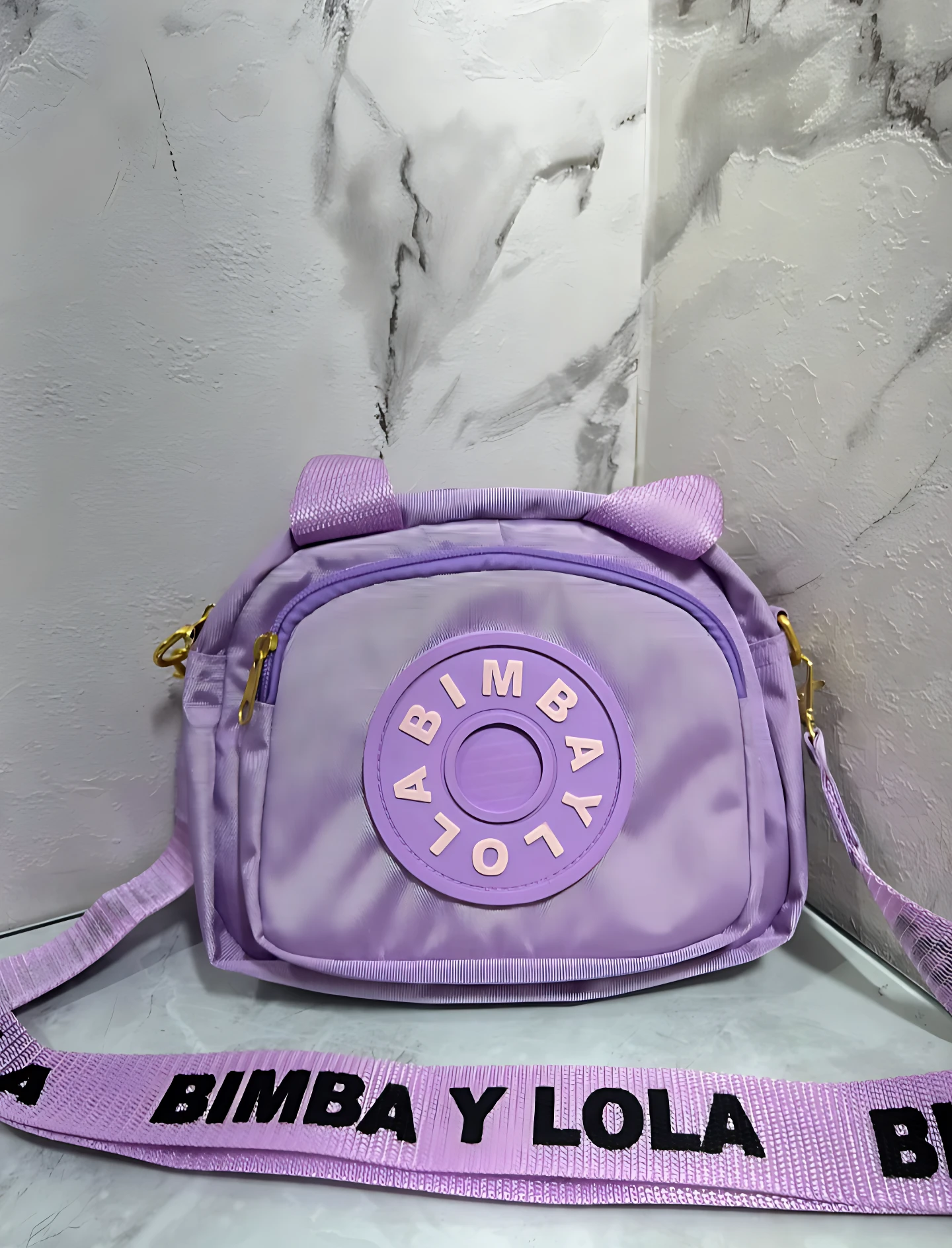 Carriel morado Bimba y Lola con logo circular y correa estampada.