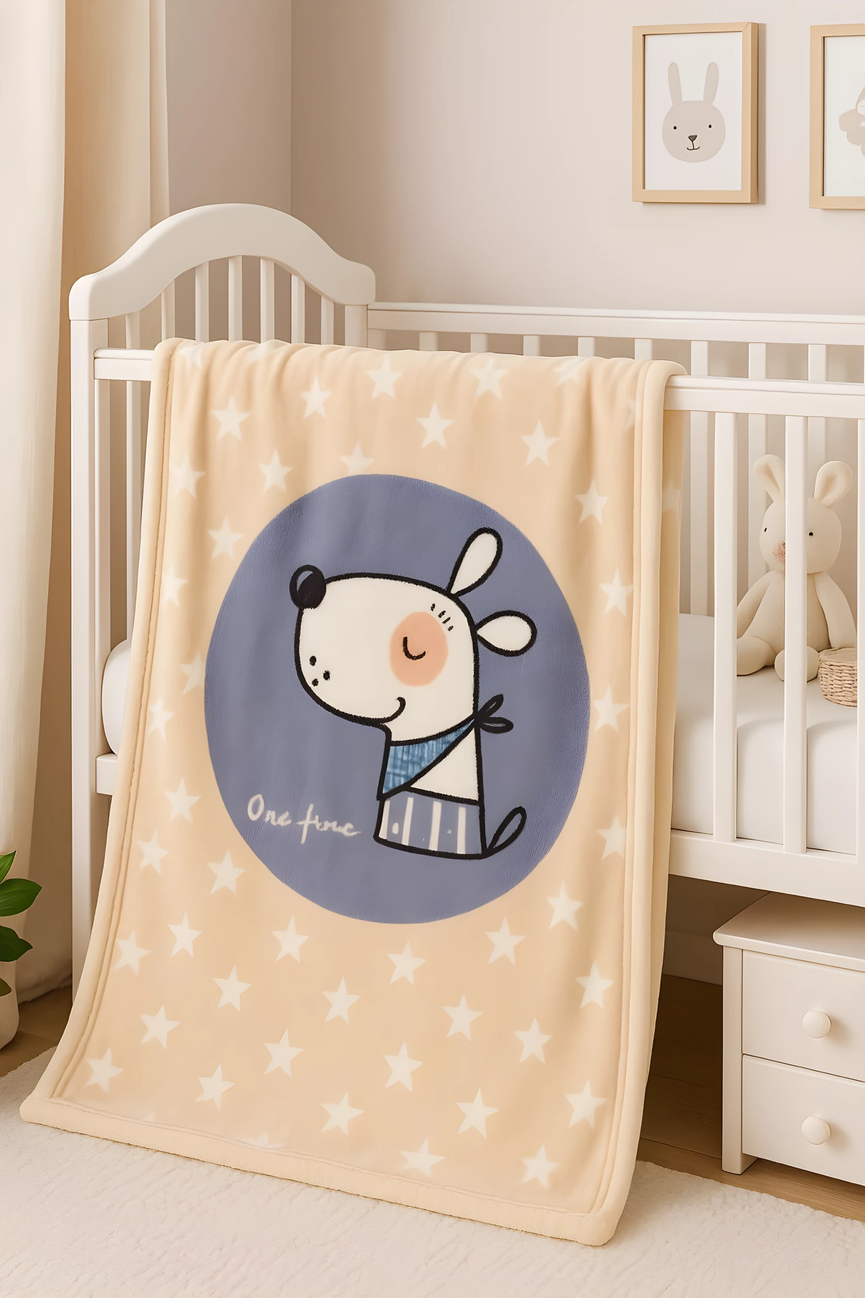 Cobija para bebé color beige con estrellas blancas y diseño de perro animado, dentro de cuna.