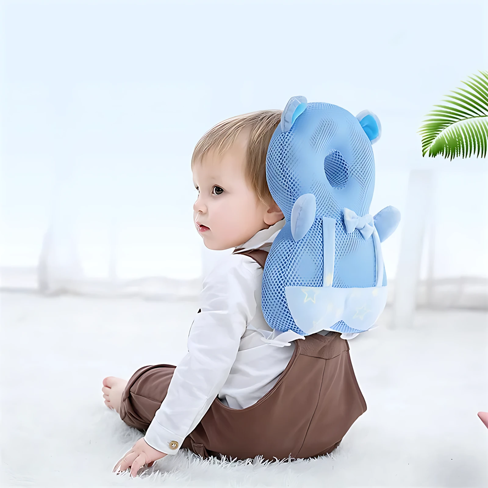 Bebé con cojín protector azul en forma de oso, sentado en alfombra blanca.
