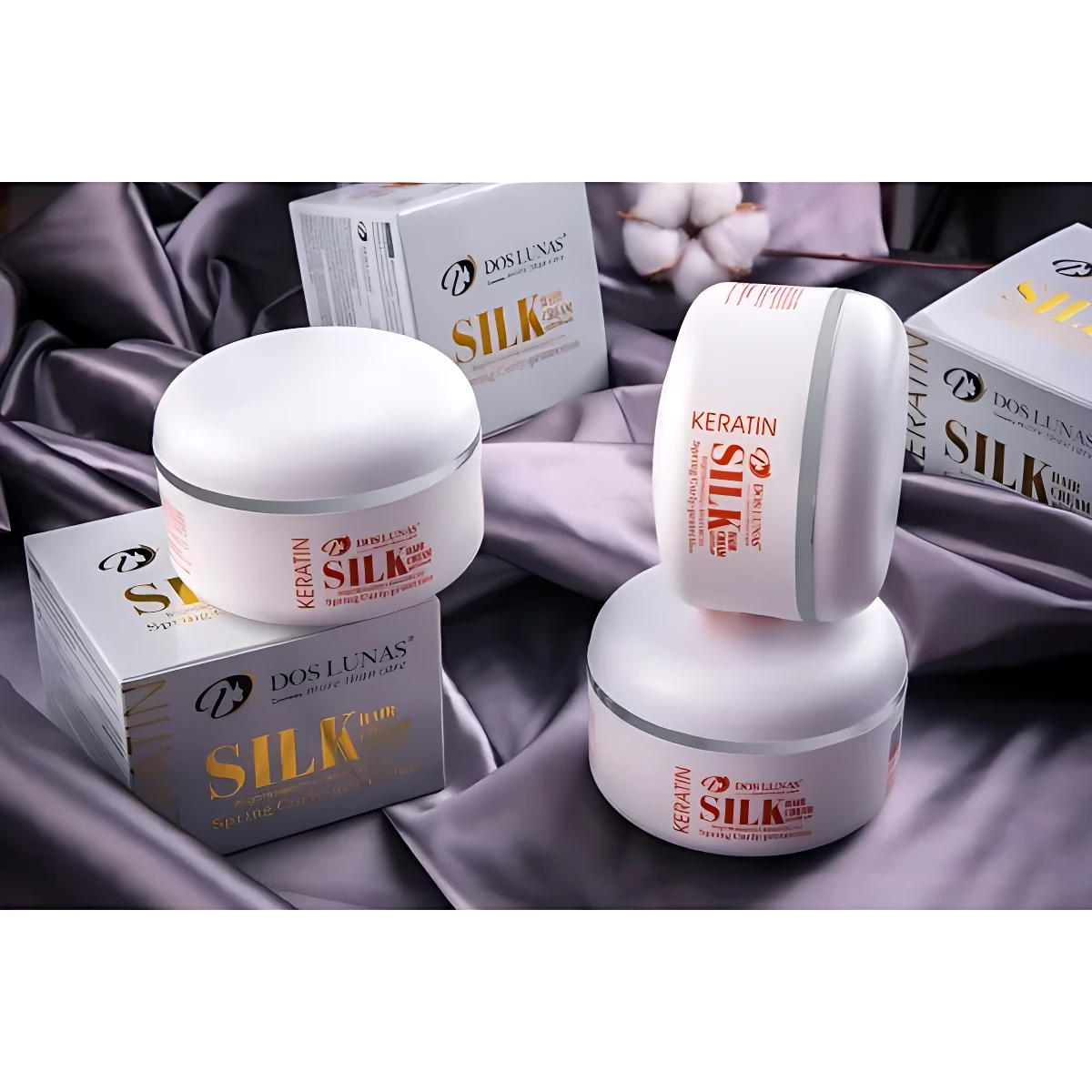 Crema para cabello "Silk" de Dos Lunas con queratina y gusano de seda, en envases blancos sobre tela satinada gris.