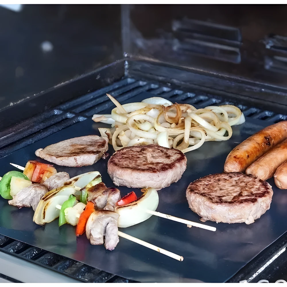 Mantas teflón antiadherente para parrilla con hamburguesas, salchichas, brochetas y cebolla asándose.