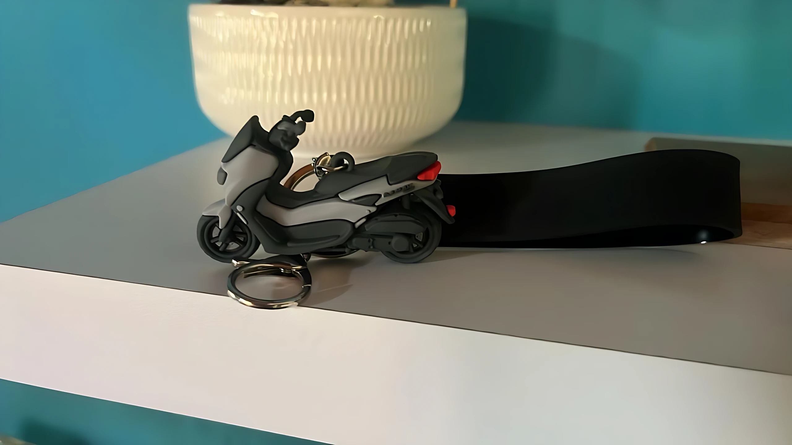 Llavero 3D Yamaha NMAX gris y negro en forma de scooter, con argolla metálica y cinta negra.