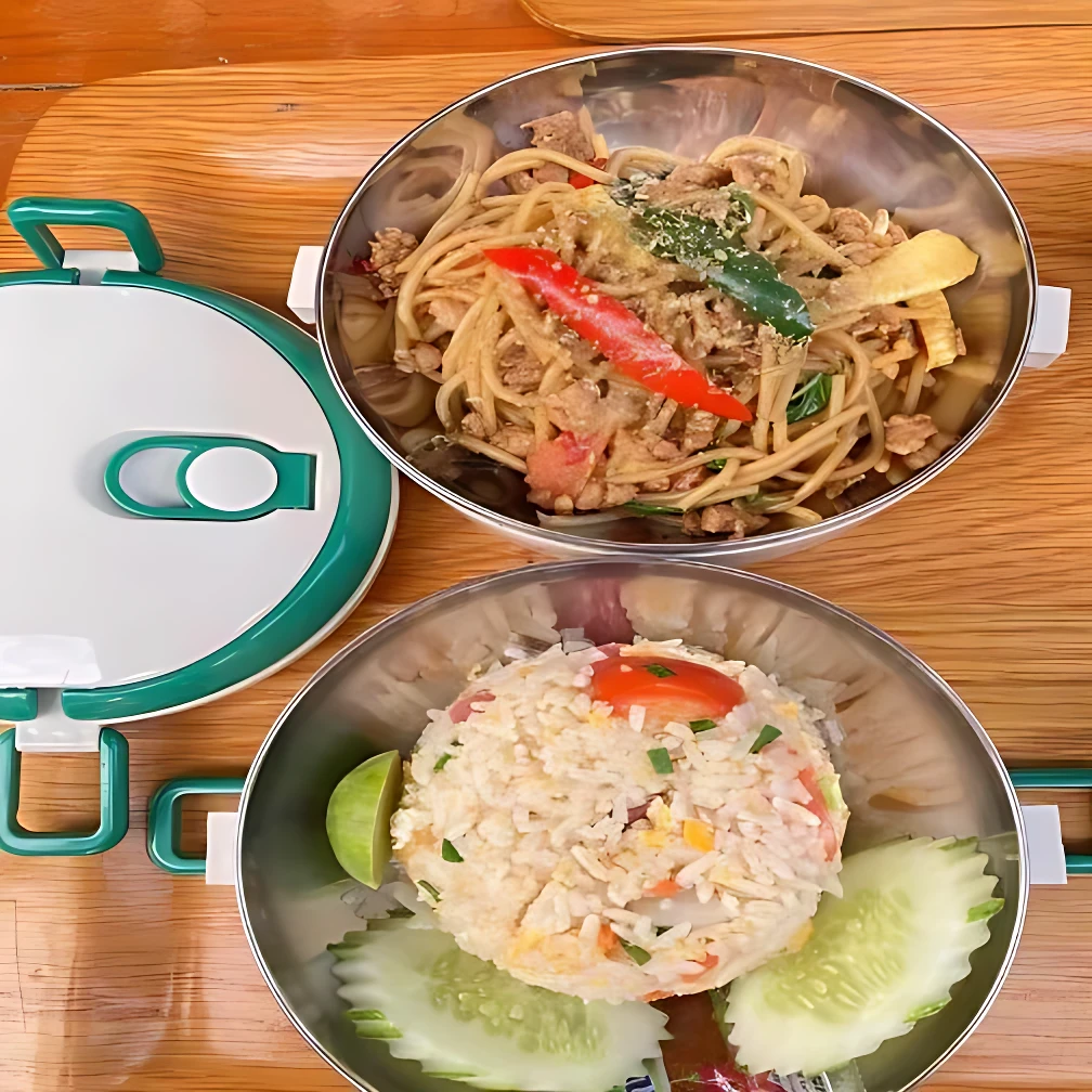 Lonchera térmica 2 niveles con espagueti y arroz frito, incluye tapa verde y cubiertos.