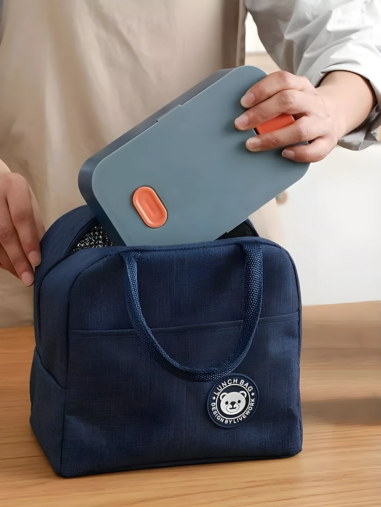 Lonchera térmica azul oscuro para comidas, con compartimento principal y detalle de oso, ideal para transportar alimentos.