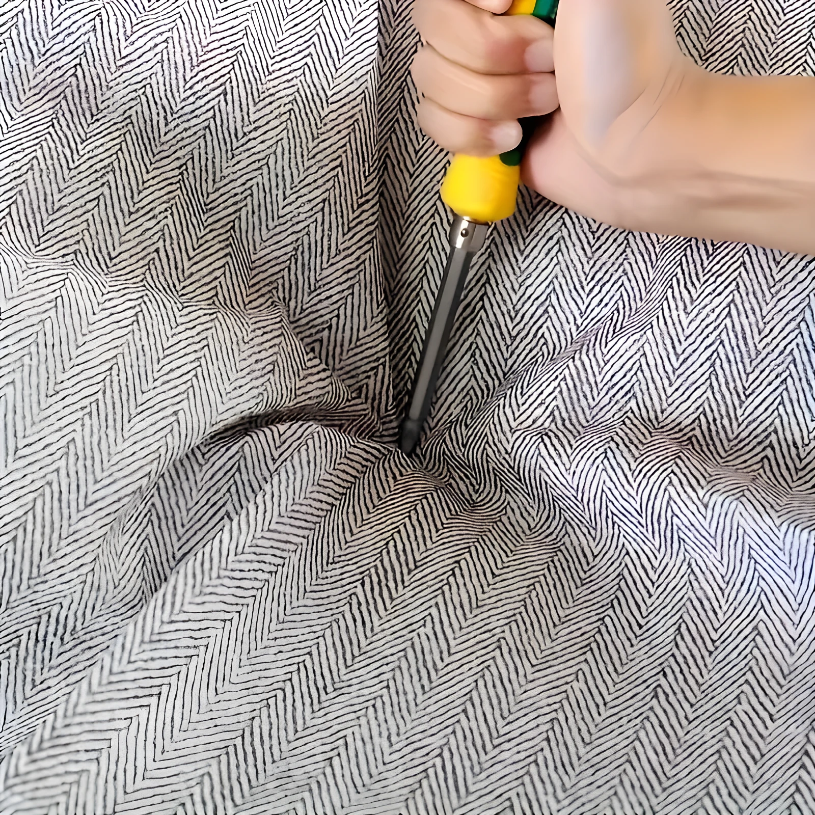 Contenedor de ropa 110L con tapa reforzada, mostrando la mano de una persona con un destornillador presionando la tela de patrón de espiga.