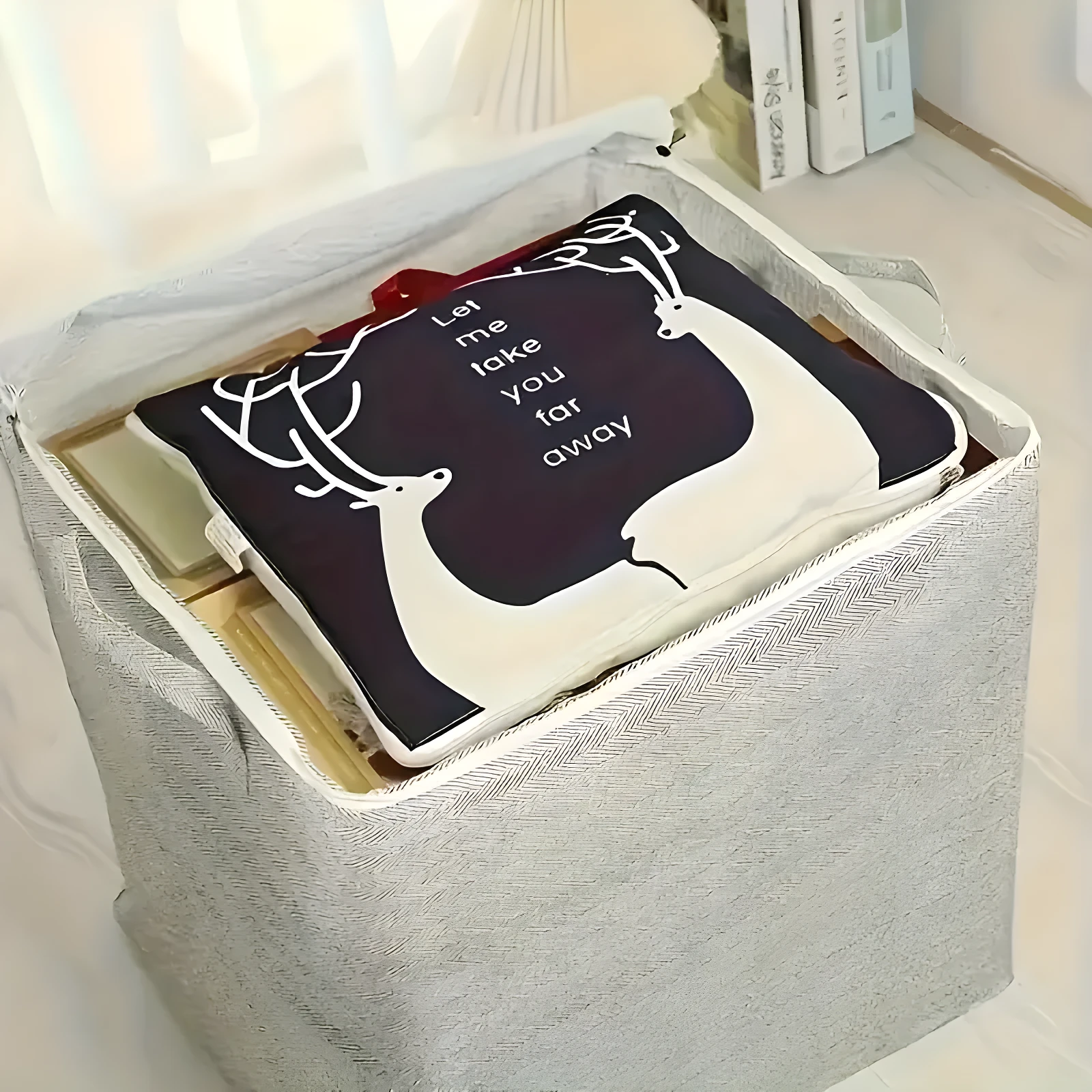 Contenedor organizador de ropa gris con funda de tela estampada con ciervos y texto "Let me take you far away".