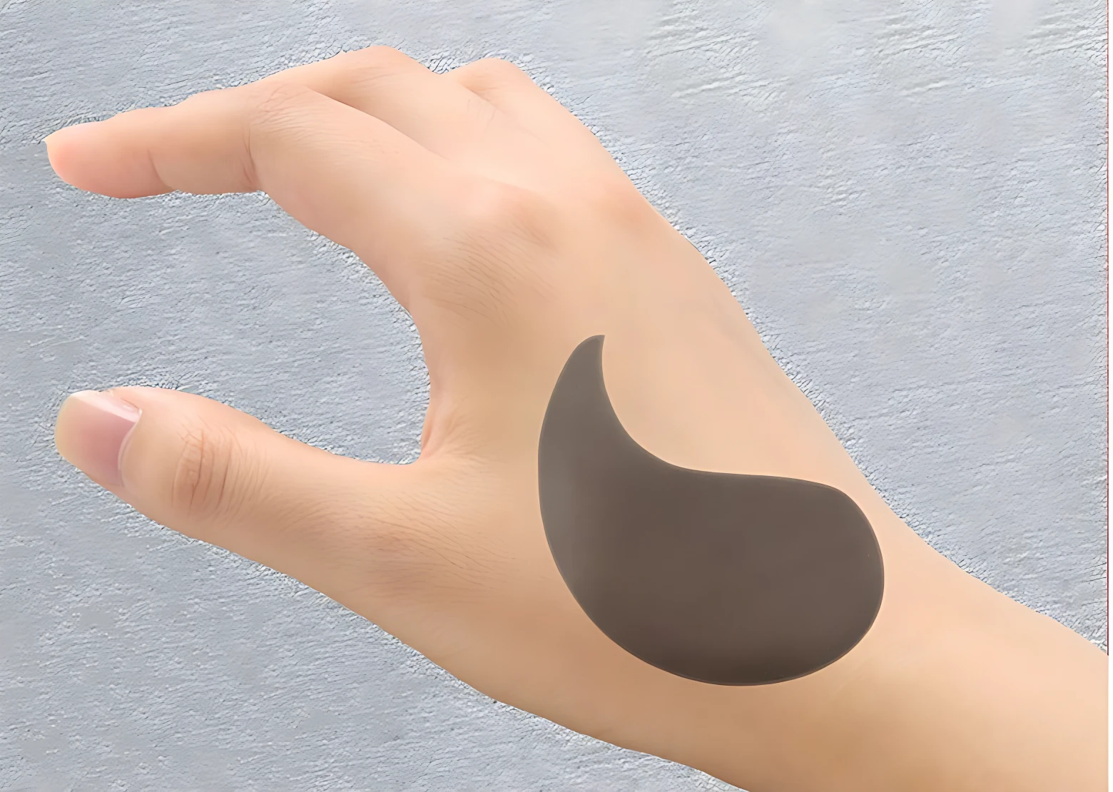 Parche negro revitalizante para ojeras y bolsas, posado sobre mano.