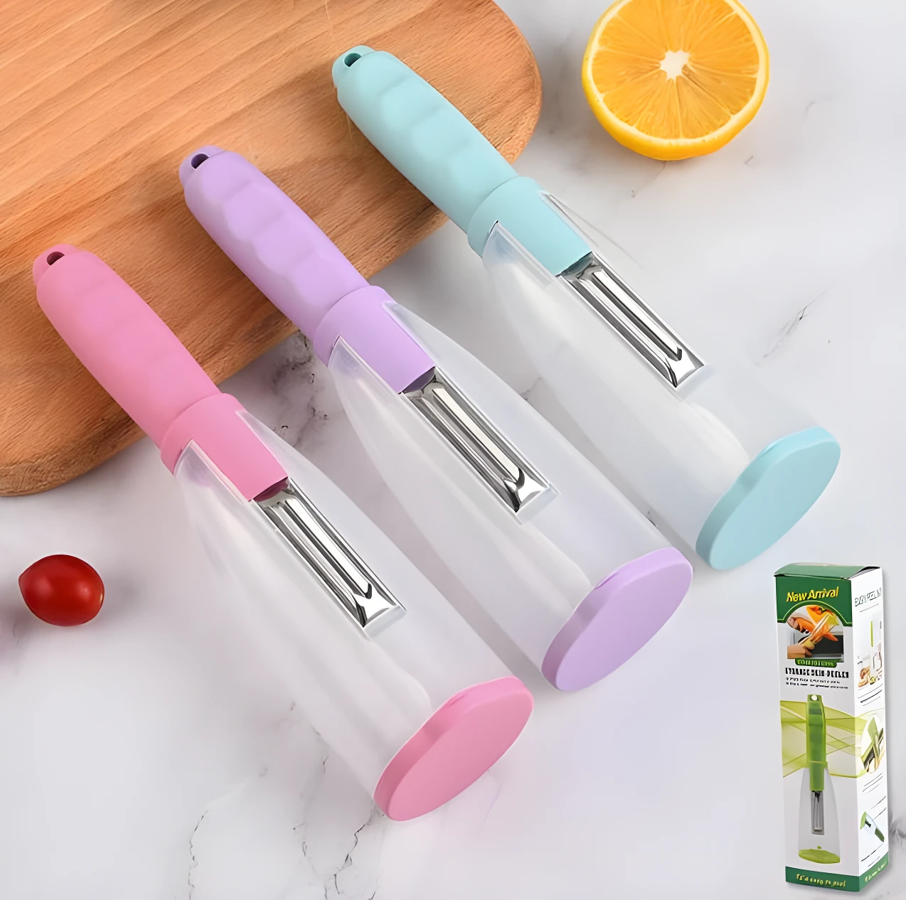 Tres peladores de verduras con depósito para cáscaras en colores rosa, lila y azul claro, sobre superficie blanca y tabla de madera.