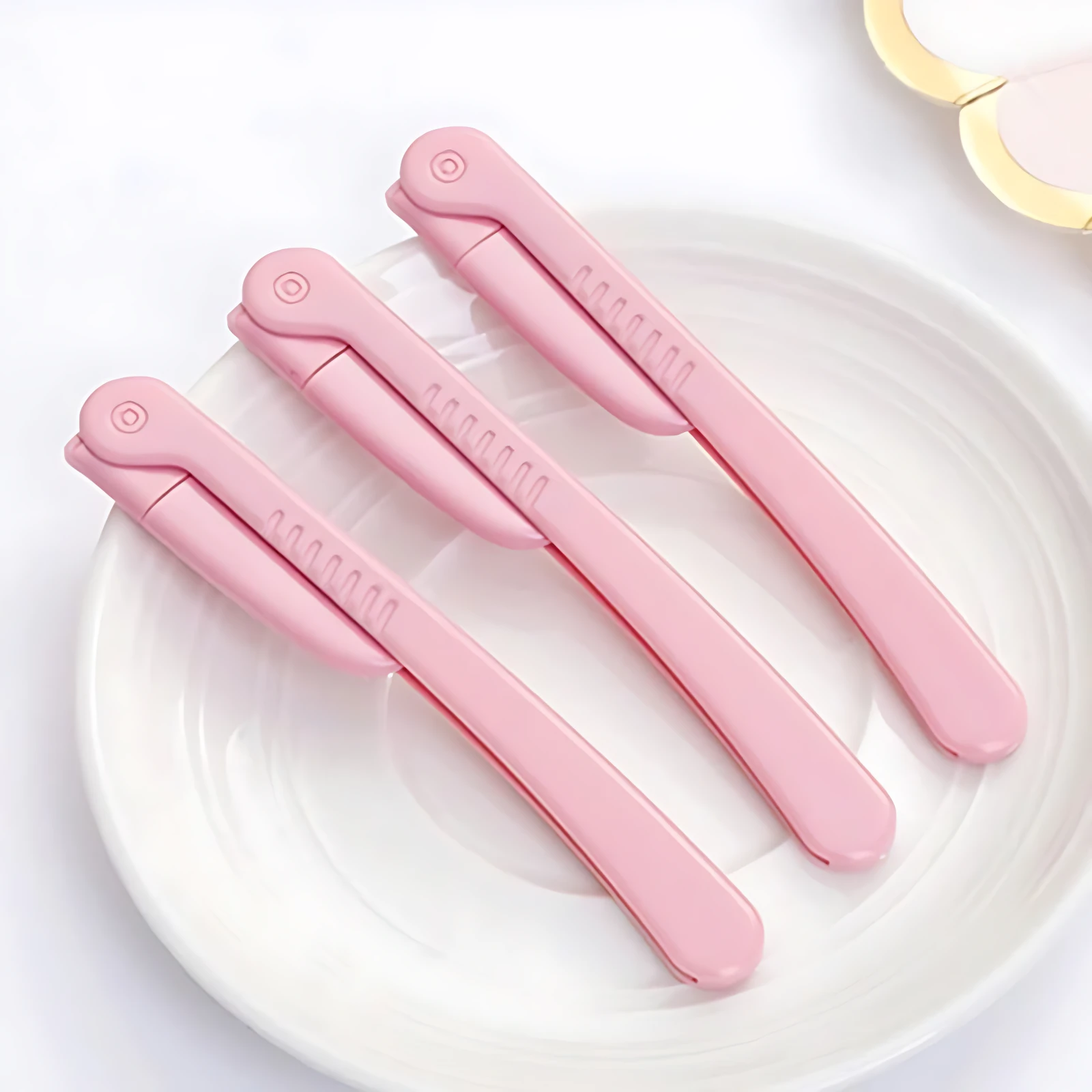 Set x3 perfiladores de cejas rosas con diseño de orejas de conejo sobre plato blanco.