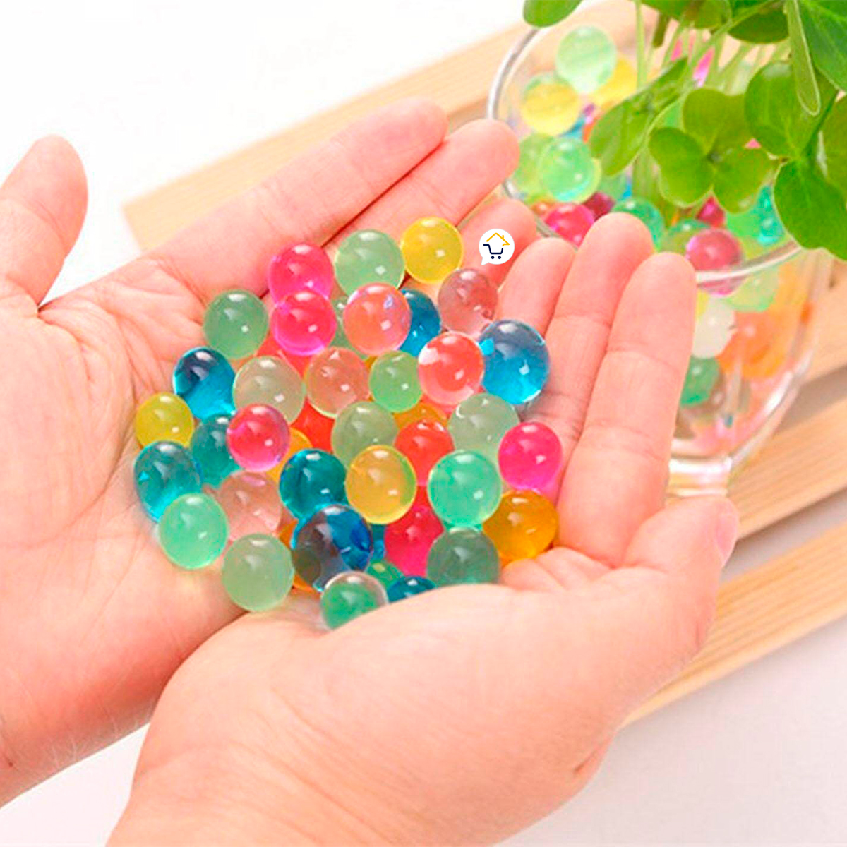 Manos sostienen perlas hidrogel decorativas de colores, brillantes y translúcidas.