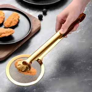 Pinzas doradas de acero inoxidable para servir y escurrir, con tres alitas crujientes en el recogedor de malla.