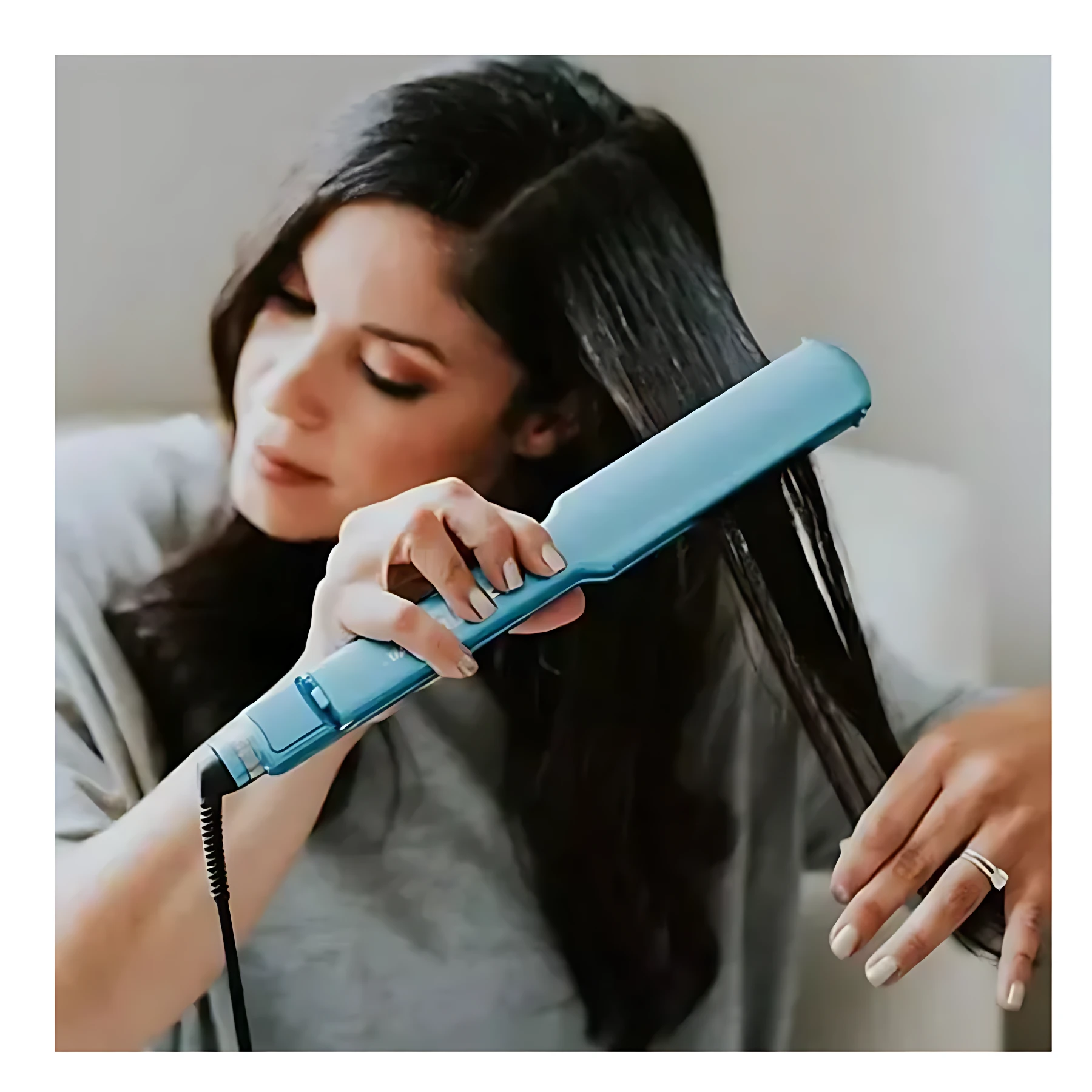 Plancha Babyliss Pro azul con placas de titanio alisando cabello oscuro.