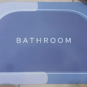 Tapete absorbente antideslizante para baño en tonos azules con borde blanco y la palabra "BATHROOM" inscrita.