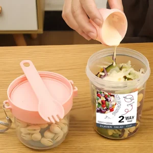 Set de 2 termos portátiles para ensaladas y snacks, uno rosa con cubiertos y otro transparente con ensalada y etiqueta "2 WAY VESSEL".